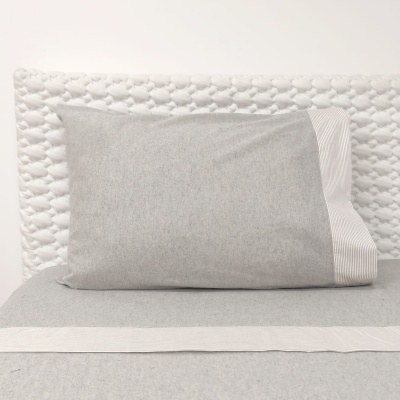 Almofada cinza claro com faixa riscada e cabeceira acolchoada branca.