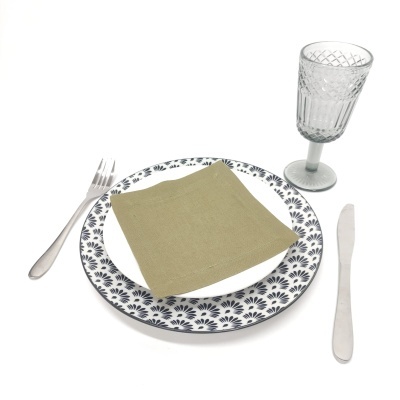 Conjunto de louça com prato floral, guardanapo verde, talheres de metal e copo de vidro texturizado