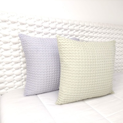 Duas almofadas texturizadas cinza claro e creme sobre cama branca