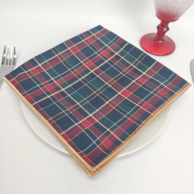 Guardanapo de tecido xadrez colorido sobre prato branco com copo vermelho e talheres