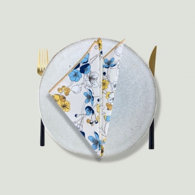Conjunto de loiça com prato cinza, talheres dourados e guardanapo floral