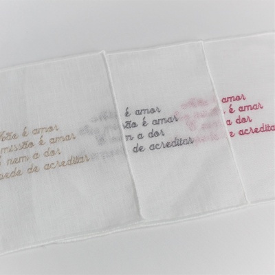 Três lenços brancos bordados com texto e marcação de lábios em várias cores
