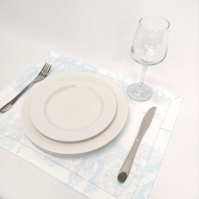 Conjunto de jantar com pratos, talheres e copo sobre guardanapo azul e branco