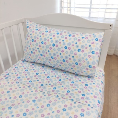 Lençóis infantis com padrão de flores coloridas numa cama branca