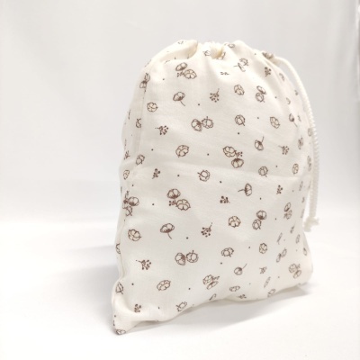 Saco de tecido branco com padrão floral castanho e fecho de cordão branco