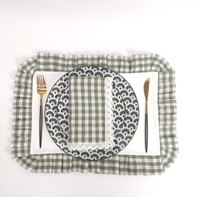 Conjunto de prato em cerâmica com padrão azul, guardanapo e toalha xadrez verde, talheres com cabo preto e dourado