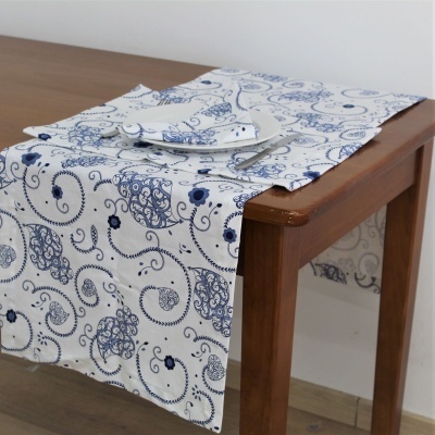 Toalha de mesa branca com padrão azul de arabescos e flores sobre mesa de madeira