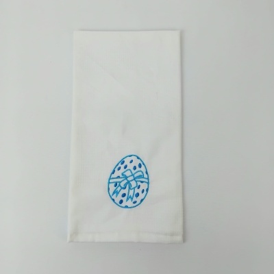 Guardanapo branco com bordado azul em forma de ovo e laço