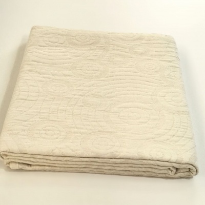 Manta creme clara com padrão em relevo dobrada sobre superfície branca