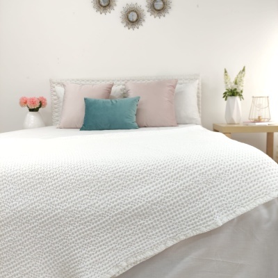 Cama com colcha branca e almofadas coloridas em quarto com decoração minimalista