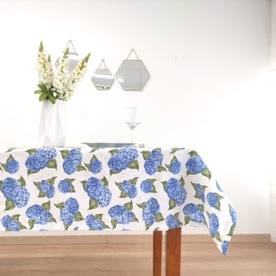 Toalha de mesa com flores azuis e vasos com flores em ambiente claro