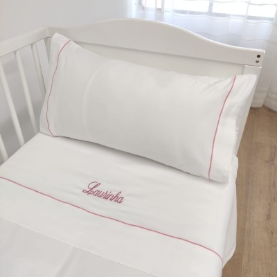 Lençóis brancos com costura vermelha e bordado Laurinha em cama infantil branca