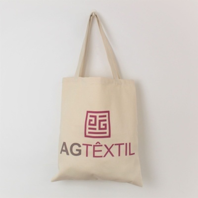 Saco de tecido creme com alças e texto AG TÊXTIL impresso
