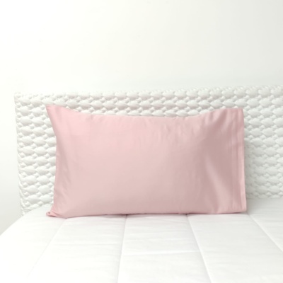 Almofada rosa sobre cama branca com cabeceira acolchoada