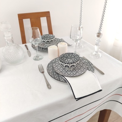 Mesa posta com pratos e tigelas em padrão preto e branco, talheres, copos, velas e castiçais