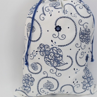 Saco de tecido branco com padrão azul de folhas e flores, cordão azul para fecho