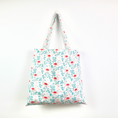 Saco de tecido branco com padrão floral em tons de vermelho, rosa e verde