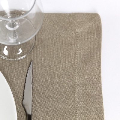 Mesa posta com guardanapo bege, faca e copo de vidro