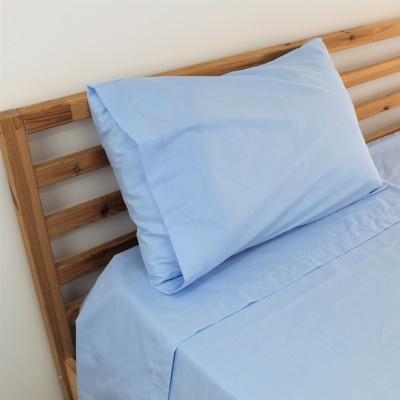 Conjunto de roupa de cama azul claro numa cama com estrutura de madeira clara