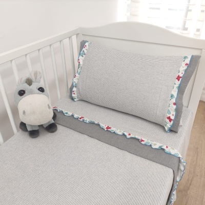 Cama de bebé com roupa de cama cinza e peluche de cavalo