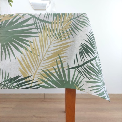 Toalha de mesa com padrão de folhas verdes e amarelas sobre fundo branco.