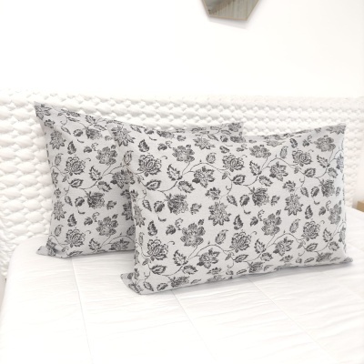 Duas almofadas florais em preto e branco sobre cama branca