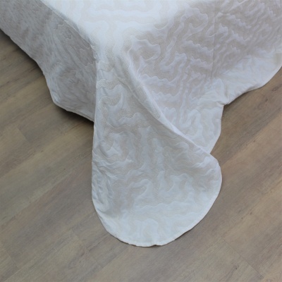 Toalha de mesa branca com padrão texturizado em relevo sobre chão de madeira