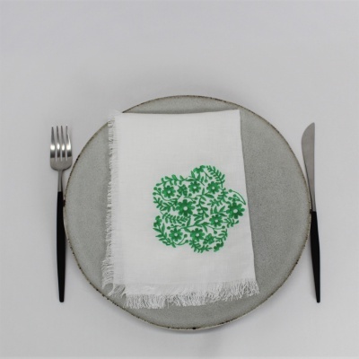 Conjunto de jantar com prato cinza, talheres pretos e guardanapo branco com padrão verde.