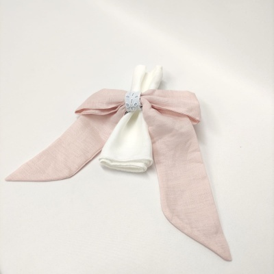 Laço rosa com detalhe azul e peça branca no centro sobre fundo branco