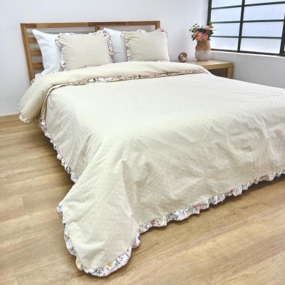 Conjunto de cama creme com bordas florais em cama de madeira num quarto com janela grande
