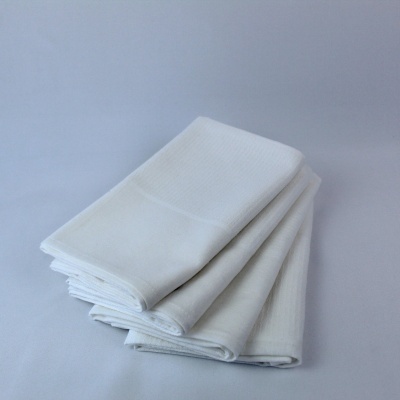 toalhas brancas dobradas em fundo cinzento claro