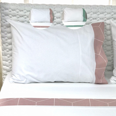 Almofada branca com detalhes geométricos rosa em cama com cabeceira estofada