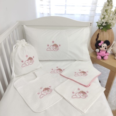 Conjunto de roupa de cama branca com bordados cor-de-rosa para berço e peluche da Minnie ao lado