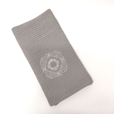 Toalha cinzenta com bordado branco em padrão circular ornamental