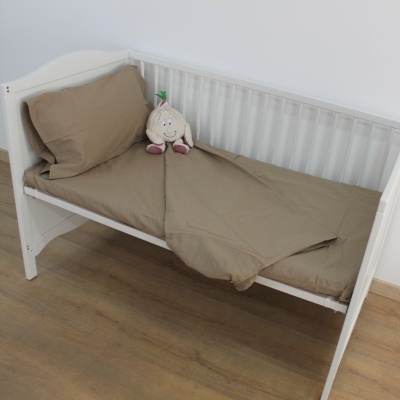 Berço branco com roupa de cama bege e peluche branco sobre a cama