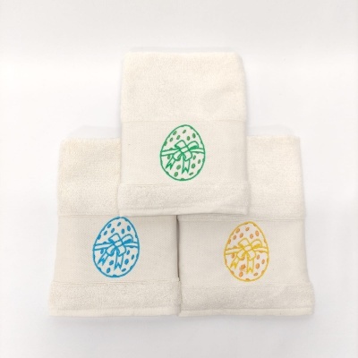 Três toalhas brancas com desenhos coloridos de ovos de Páscoa