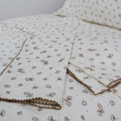Conjunto de roupa de cama branco com padrão castanho de flores pequenas e borda detalhada