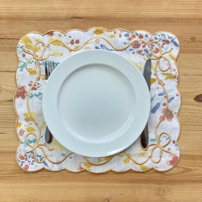 Prato branco, garfo e faca sobre individual floral colorido e madeira clara