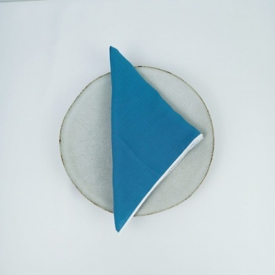 Guardanapo azul com borda branca sobre prato cinza