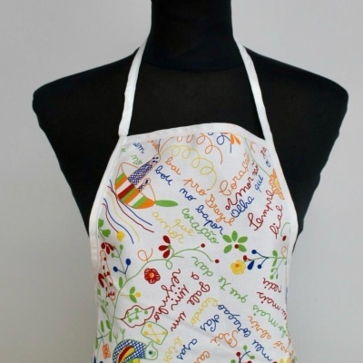 Avental colorido com padrões florais e textos coloridos, em manequim preto