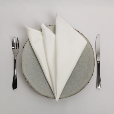 Mesa posta com prato cinza, guardanapos brancos, garfo e faca