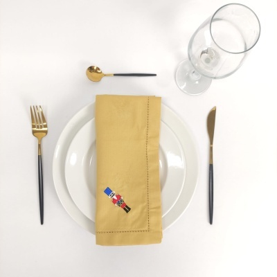 Conjunto de loiça branca com guardanapo amarelo, talheres pretos e dourados e copo transparente