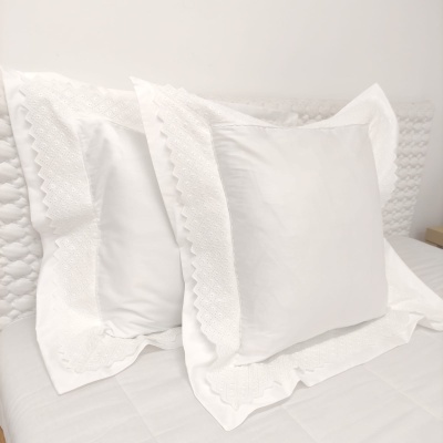 Par de fronhas brancas bordadas com renda em cama branca