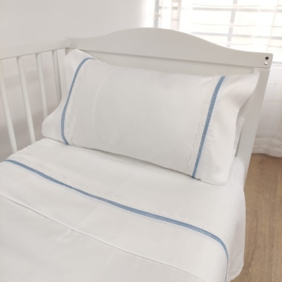 Jogo de cama branco com bordado azul num berço branco