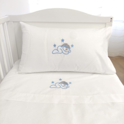 Lençol e fronha de berço brancos com bordado de bebé a dormir