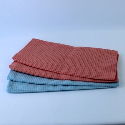 Três panos de cozinha azul claro e vermelho com padrão waffle empilhados