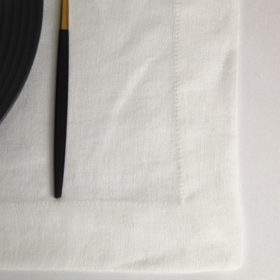 Guardanapo branco em tecido com objecto preto e amarelo e prato preto ao lado