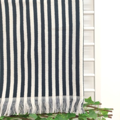 Tapete ou manta riscada azul escuro e branco com franjas pendurado