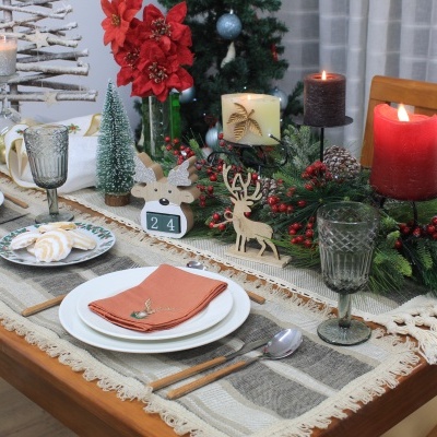 Mesa de jantar decorada para Natal com pratos, guardanapos, velas e enfeites em madeira.