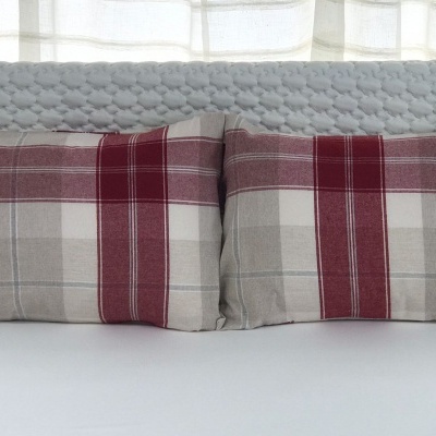 Cabeceira cinza com almofadas xadrez em cama branca